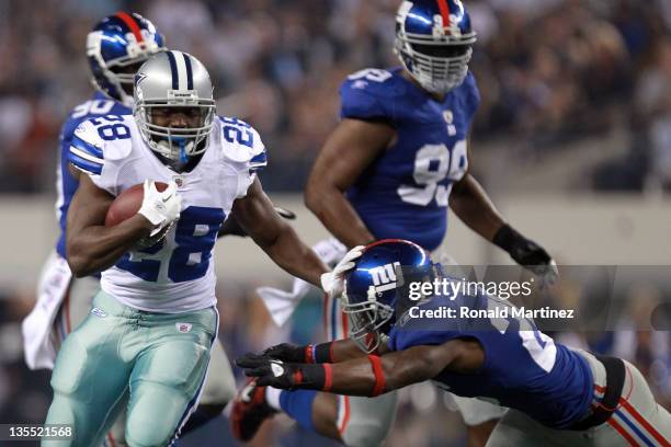 Running back Felix Jones of the Dallas Cowboys runs the ball as he break a tackle by Antrel Rolle of the New York Giants for a 26-yard gain in the...