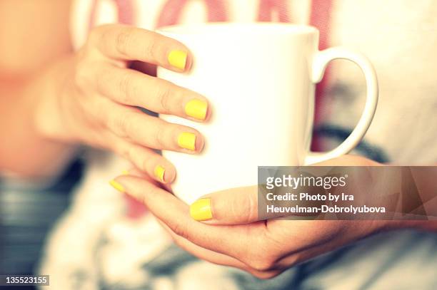 cup of coffee/tea in hands of woman - yellow nail polish stock-fotos und bilder