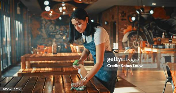 shot of a young woman disinfecting the tables while working in a restaurant - juicer stock pictures, royalty-free photos & images