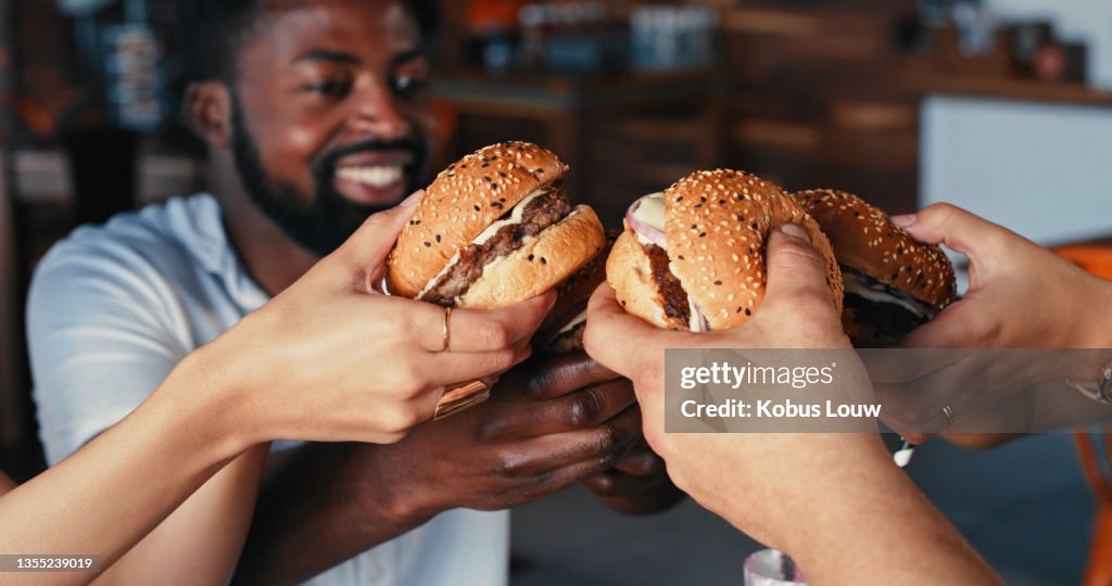 Shot of a group of young friends enjoying delicious hamburgers at a diner