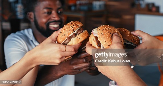 Shot of a group of young friends enjoying delicious hamburgers at a diner Shot of a group of young friends enjoying delicious hamburgers at a diner