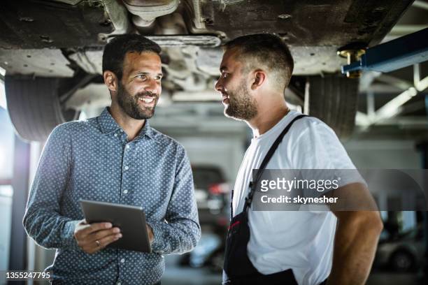 happy manager and auto mechanic talking while using touchpad in a workshop. - touchpad stock pictures, royalty-free photos & images