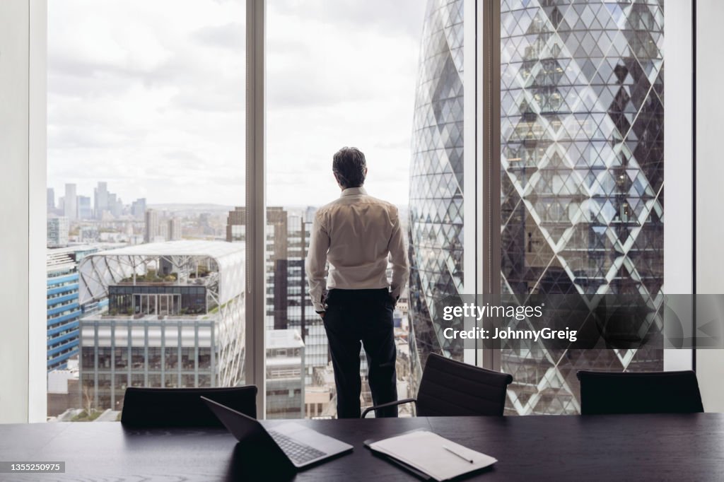 Nachdenklicher britischer Geschäftsmann mit Blick aus dem Fenster
