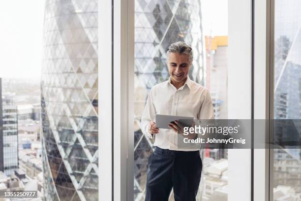 london executive using digital tablet in modern office - businessman city imagens e fotografias de stock