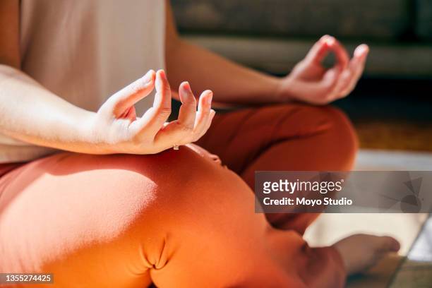 cropped shot of an unrecognisable woman sitting alone and meditating in her living room at home - mudra stock pictures, royalty-free photos & images