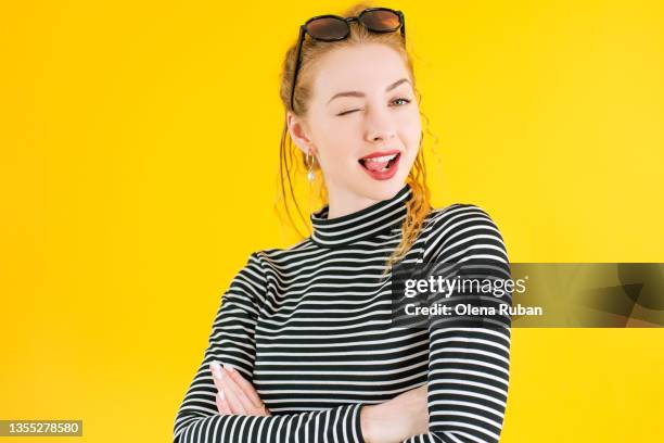 blinking young woman sticking out tongue with crossed arms. - eyelid stock pictures, royalty-free photos & images