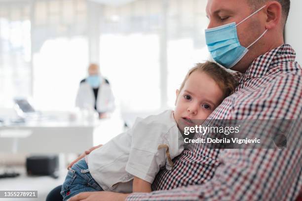 man with protective mask consoling his daughter at doctor's office - receiving treatment concerned stock pictures, royalty-free photos & images