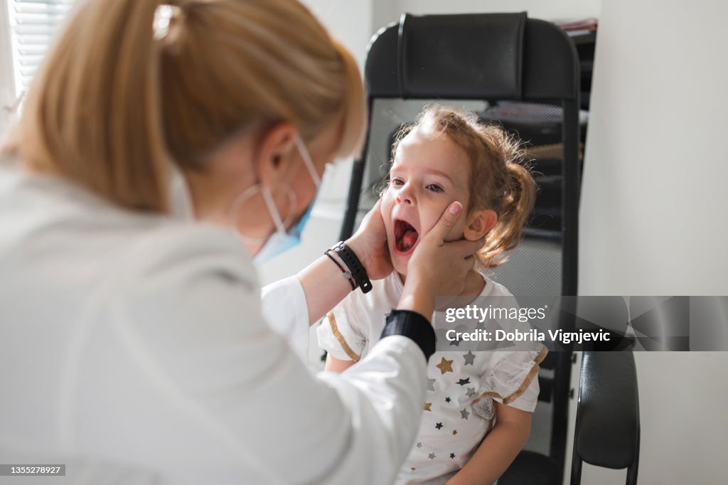 Young child having her tonsils and throat checked by a female doctor
