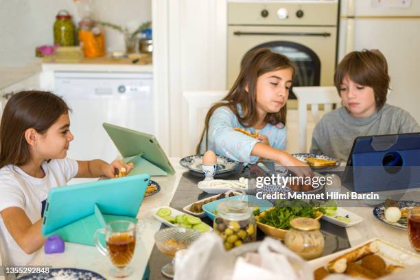 bambini che usano il tablet digitale all'ora di colazione - famiglia multimediale foto e immagini stock