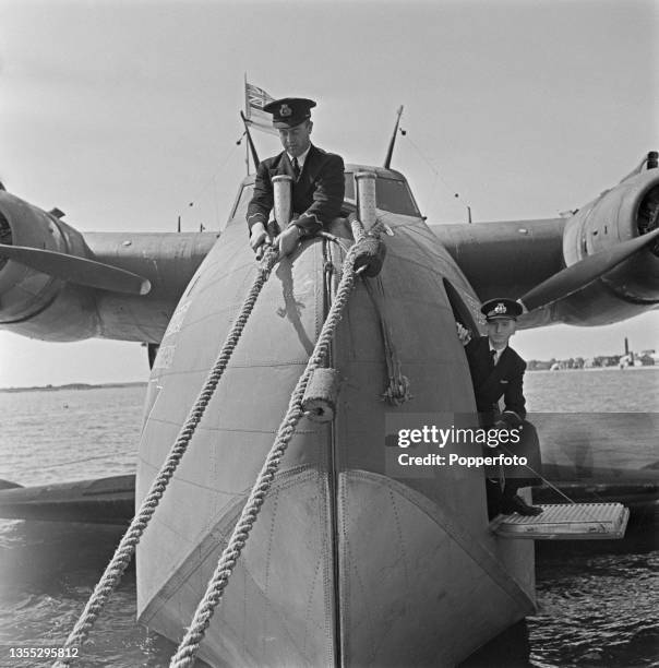 Two members of the cabin crew cast off the mooring ropes from the British Overseas Airways Corporation Boeing 314A Clipper flying boat Berwick prior...