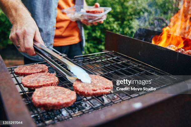 aufnahme eines mannes beim grillen von burgern - grillzange stock-fotos und bilder