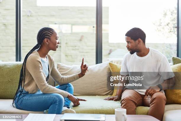 shot of a young couple having a disagreement at home - bossy husband stock pictures, royalty-free photos & images