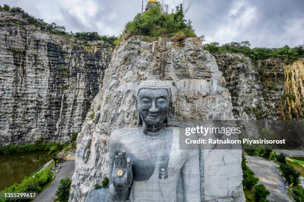 aerial drone view sunrise scene of stone buddha statue at wat khao tham thiam, suphanburi province, thailand. - suphan buri province stock-fotos und bilder