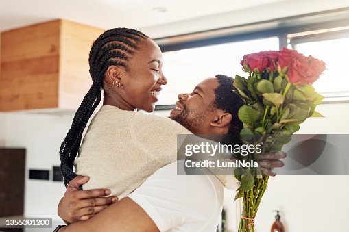 Photo d’un jeune homme surprenant sa femme avec un bouquet de fleurs à la maison Photo d’un jeune homme surprenant sa femme avec un bouquet de fleurs à la maison