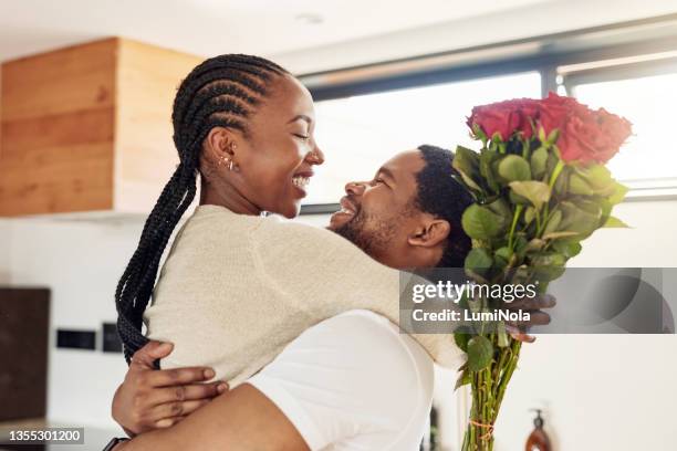 shot of a young man surprising his wife with a bunch of flowers at home - romance flowers stock pictures, royalty-free photos & images