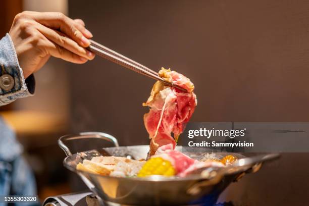 tasting sukiyaki on the table - hot pots stock-fotos und bilder