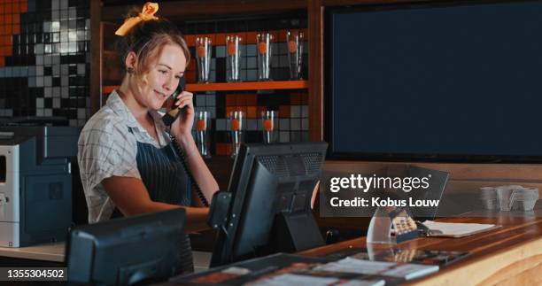 foto de una joven hablando por teléfono detrás del mostrador de un restaurante - telefono fijo fotografías e imágenes de stock