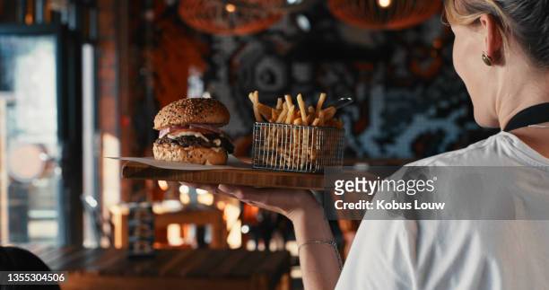 shot of a waitress serving a burger with fries at a restaurant - south africa food stock pictures, royalty-free photos & images