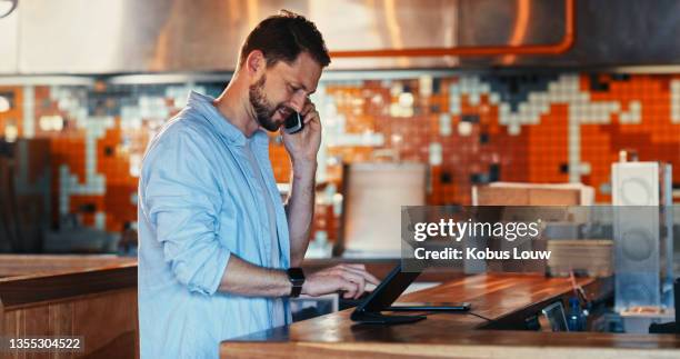 shot of a young man using a digital tablet while working behind the counter of a restaurant - restaurant manager phone stock pictures, royalty-free photos & images