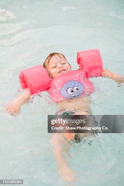 small red-headed toddler floating on his back in pool with floaty on in buffalo, ny - freestyle swimming stock pictures, royalty-free photos & images