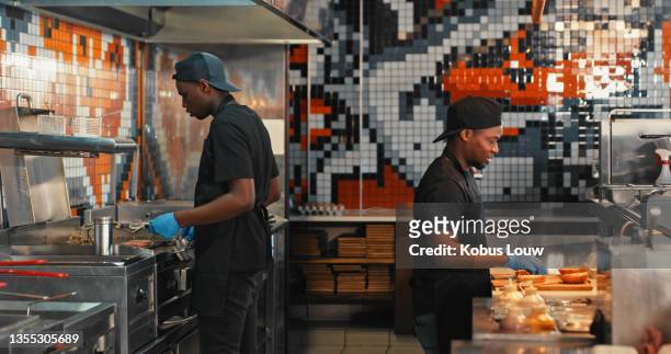 shot of a chef preparing food in a commercial kitchen at a restaurant - burger on grill imagens e fotografias de stock