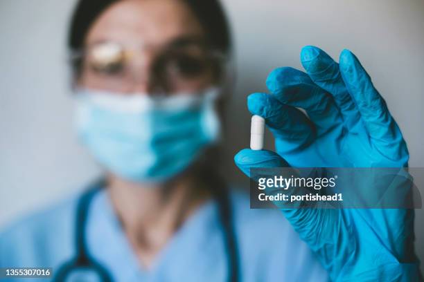 infectious doctor holding covid 19 antiviral drug - medicamento antiviral imagens e fotografias de stock