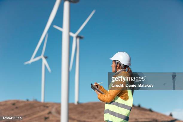 female wind energy engineer working in wind farm. renewable energy. - power occupation stock pictures, royalty-free photos & images