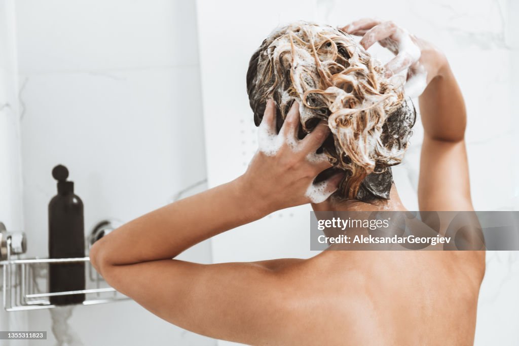 Rear View Of Female Washing Hair In Shower