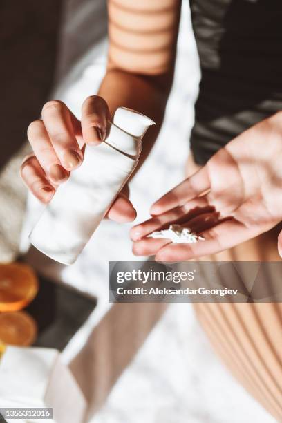 female putting favorite skincare cream in hand at home - ointment stock pictures, royalty-free photos & images