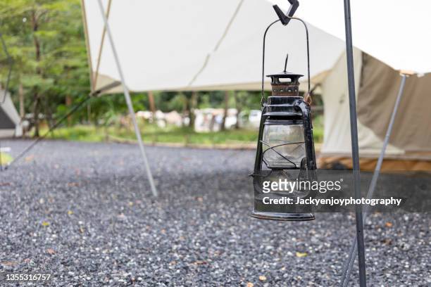 a vintage lantern near a tent in the forest - ランタン ストックフォトと画像