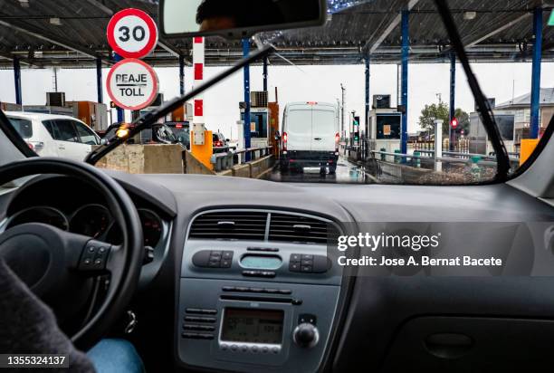 car point of view driving. cars approaching the toll booth on a rainy highway. - pedaggio foto e immagini stock