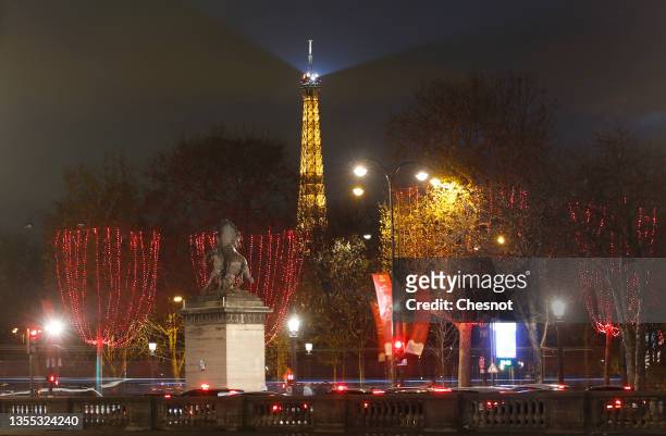 Red Christmas lights decorate the trees to illuminate the Champs-Elysees avenue with the illuminated Eiffel Tower in the background for Christmas and...