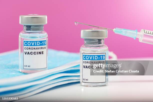coronavirus covid-19 vaccine. syringe near glass vials and face protective masks. - covid vaccination stock pictures, royalty-free photos & images