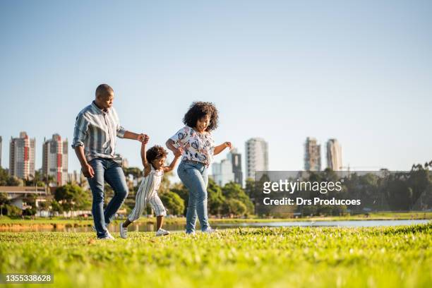 family strolling in the late afternoon in the city park - city life stock pictures, royalty-free photos & images