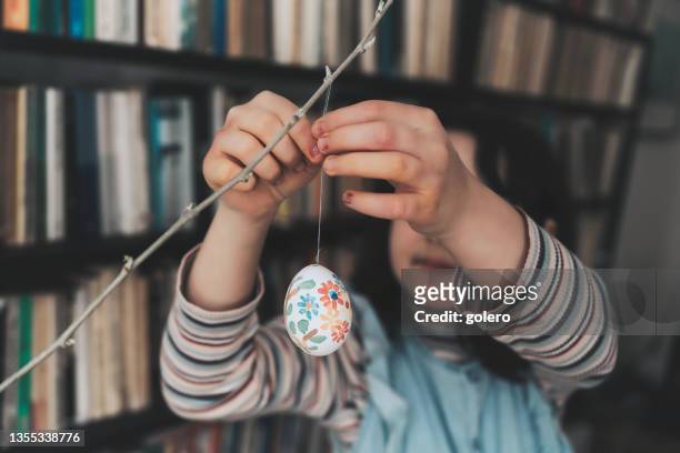 little girl decorating branch with self painted easter egg - easter fantasy stockfoto's en -beelden