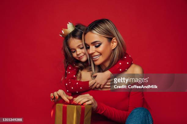 glückliche mutter mit baby kind, die ein geschenk öffnet - christmas studio stock-fotos und bilder