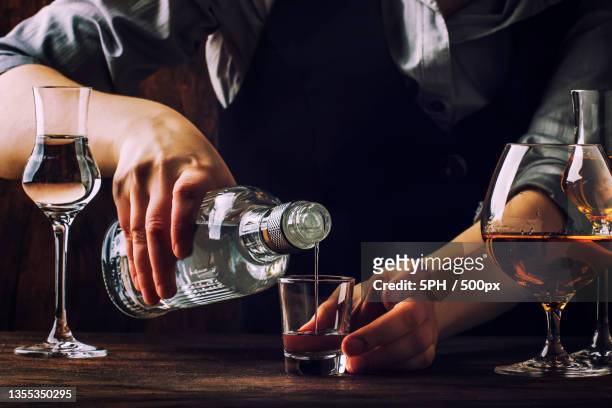 midsection of man pouring alcohol in glass on table - chocolate bar stock-fotos und bilder
