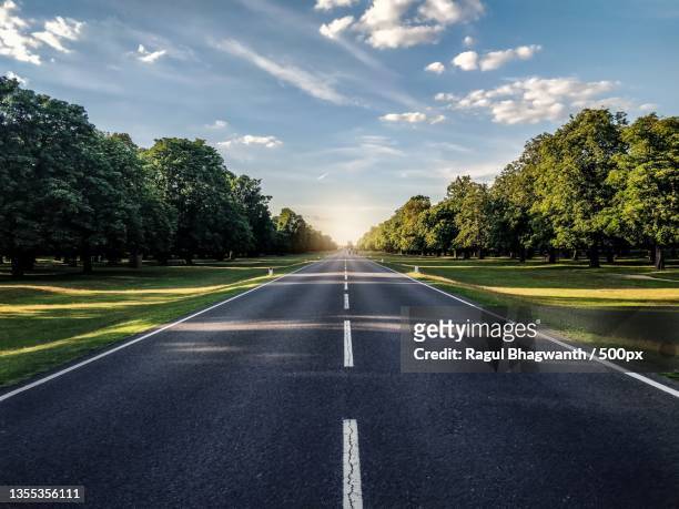 empty road amidst trees against sky - strada foto e immagini stock