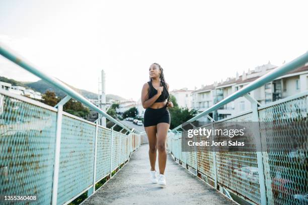 woman running on a urban bridge - voluptuous black women stockfoto's en -beelden