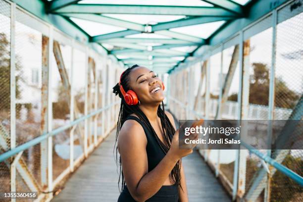 woman using a smartphone and headphones after workout - bluetooth stock-fotos und bilder