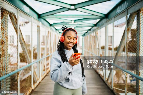 woman using a smartphone and headphones after workout - hören stock-fotos und bilder