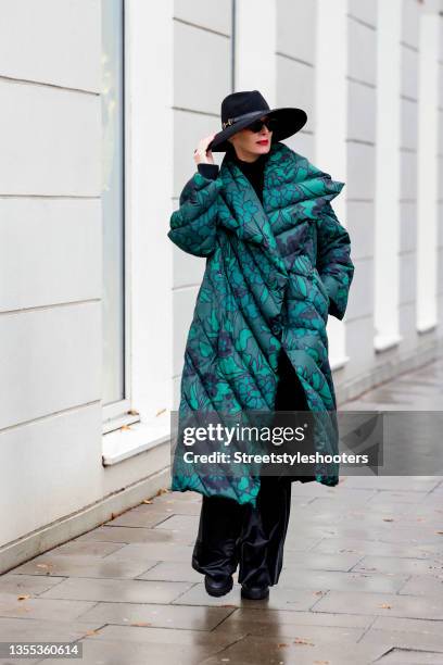 Best Ager Model and Influencer Petra van Bremen wearing a green long puffer coat with floral print by Christian Wijnants, a black turtleneck pullover...