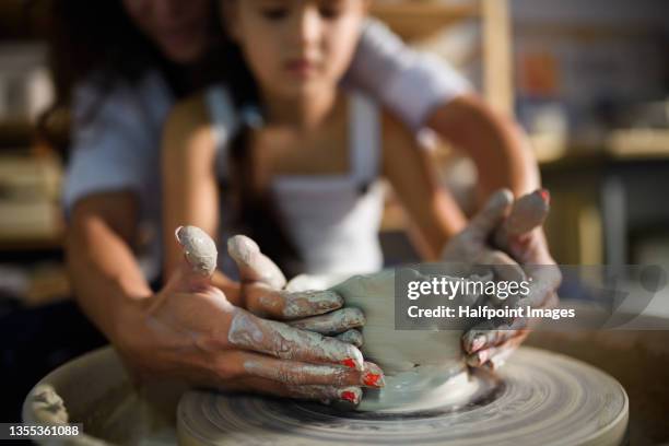 unrecognizable mother and her little daughter learning pottery on a pottery wheel. - aardewerk stockfoto's en -beelden