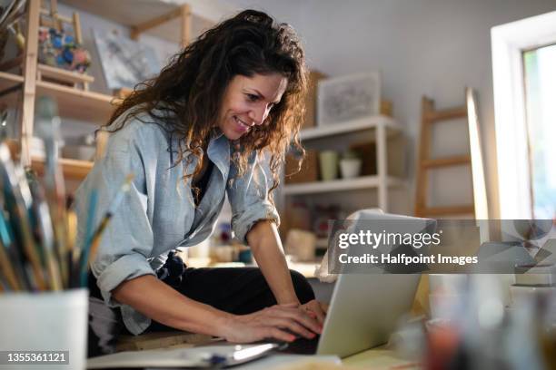 mid adult potter woman, using laptop indoors in art studio small business concept. - craftsman 個照片及圖片檔