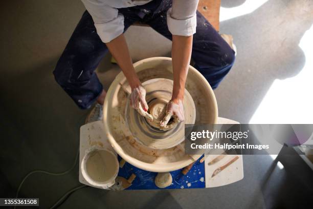 top view of unrecognizable woman, making pottery on a pottery wheel in art studio. - pottery stock pictures, royalty-free photos & images