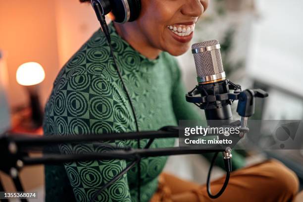 smiling young woman recording podcast - radio stockfoto's en -beelden