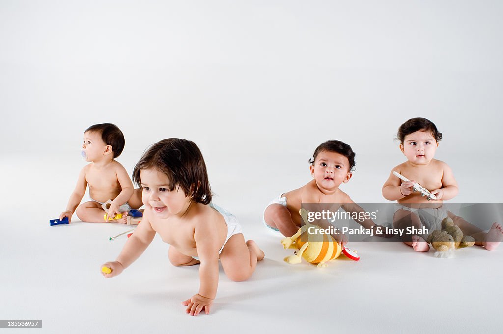 Four babies sitting playing with toys