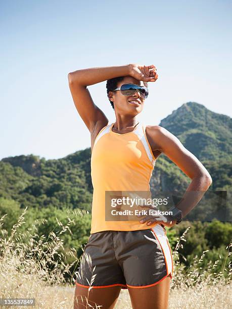 fatigued mixed race runner stopping in field - joggeuse photos et images de collection