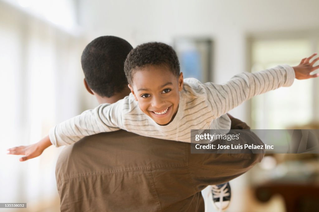 African American father carrying son on shoulders