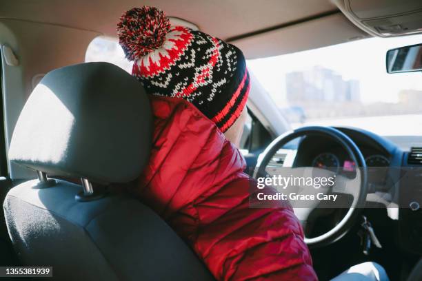 man drives car in bright red jacket and knit hat - red coat stock-fotos und bilder